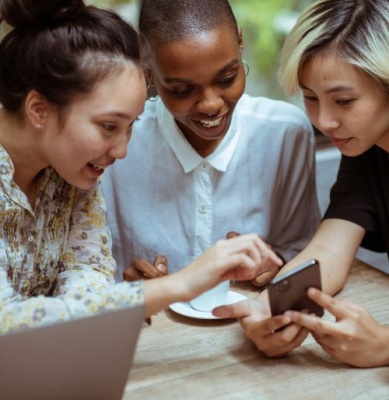 three young  woman looking at a mobile phone