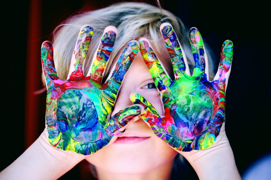 Young boy with painted hands at his face